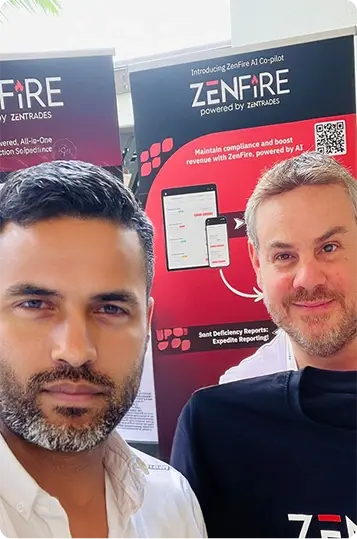 Two men at a trade show posing in front of ZenFIRE banners promoting AI-powered features or solutions.